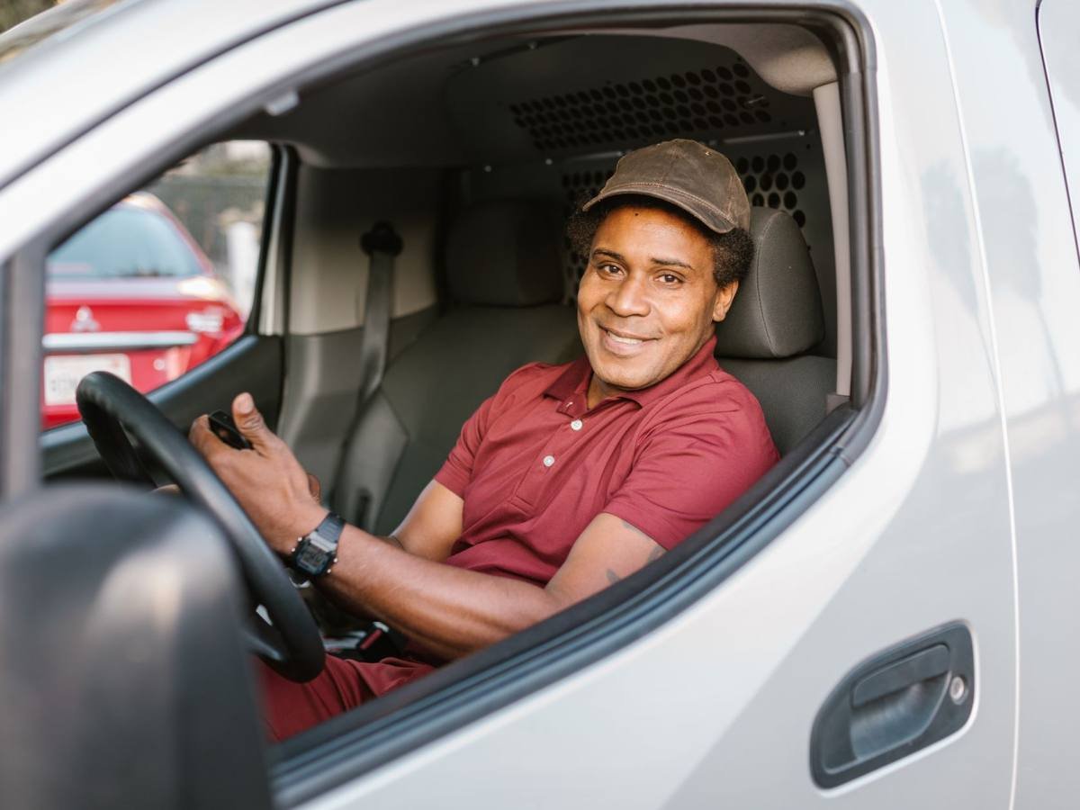 A van driver smiling by their vehicle